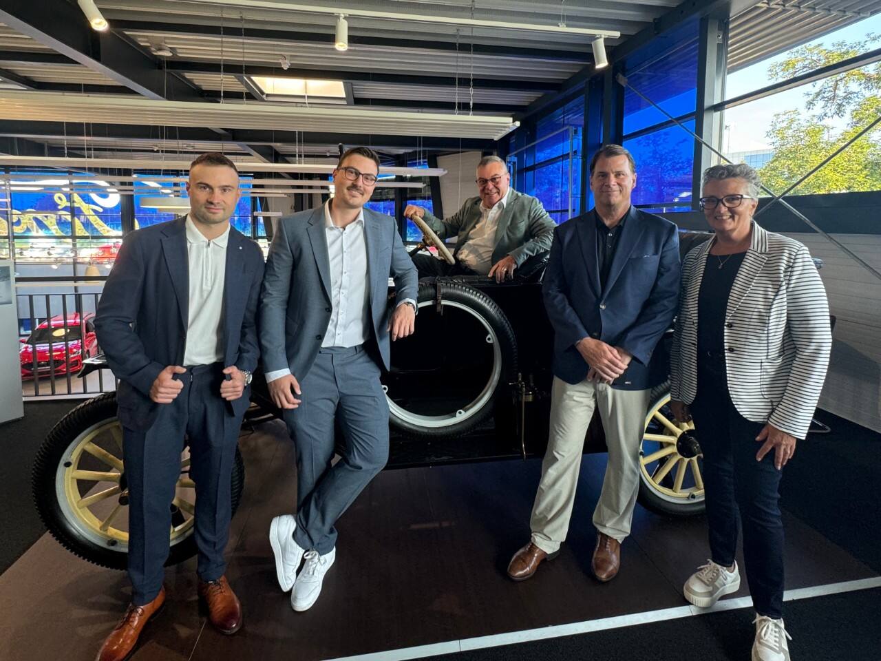 A group of men pose near a tire.